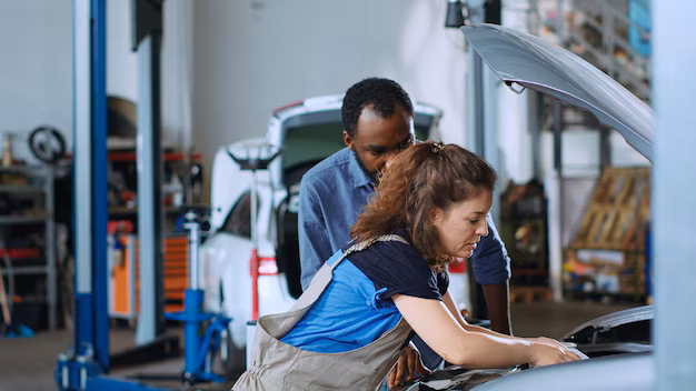 female mechanic working on car engine while a customer watches